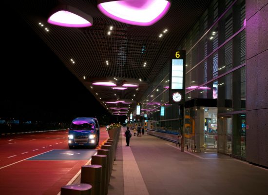 Night view of Singapore's Changi Airport entrance with illuminated canopy and bus.